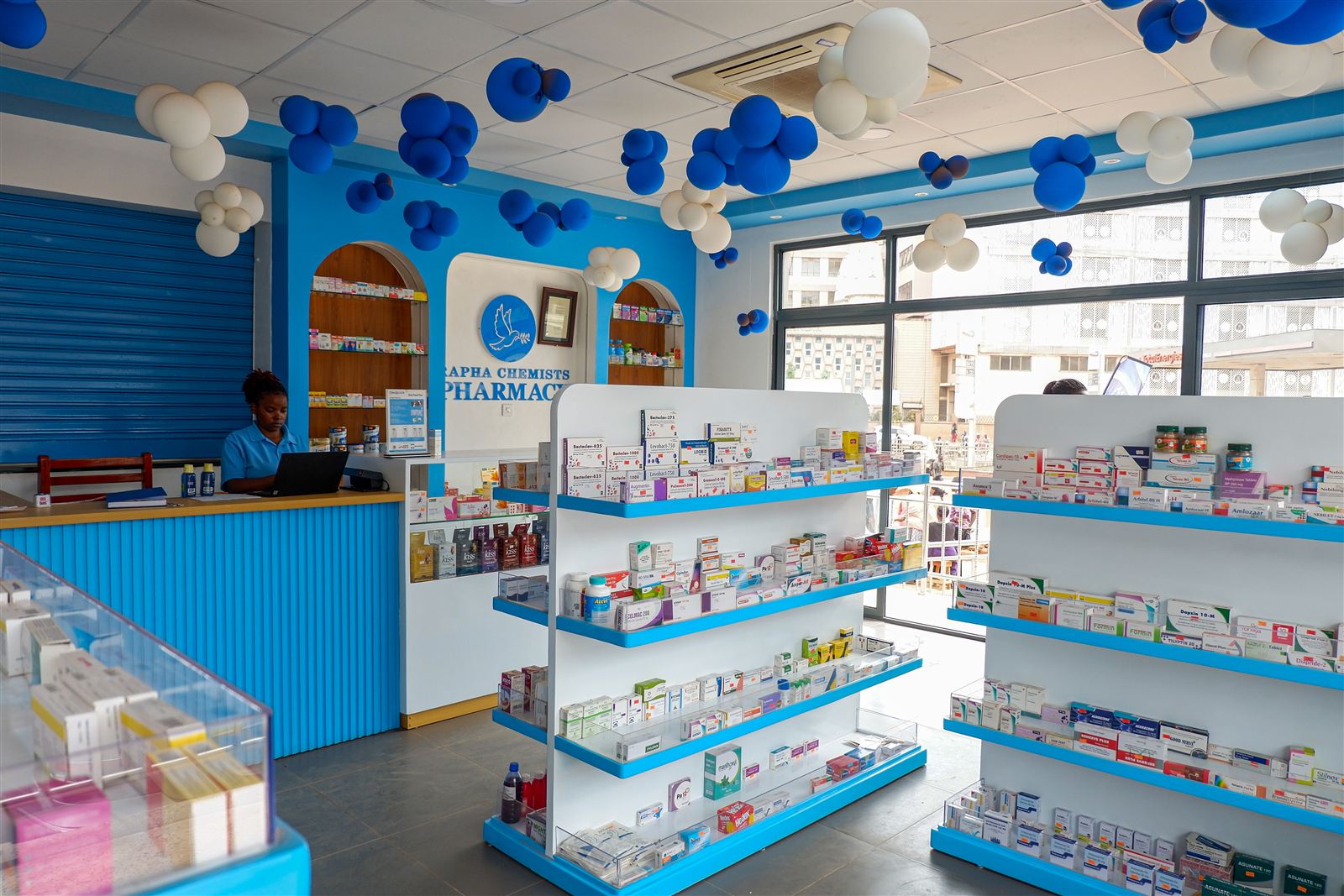 Inside Rapha Chemists Pharmacy with medicine shelves and blue-and-white decorations