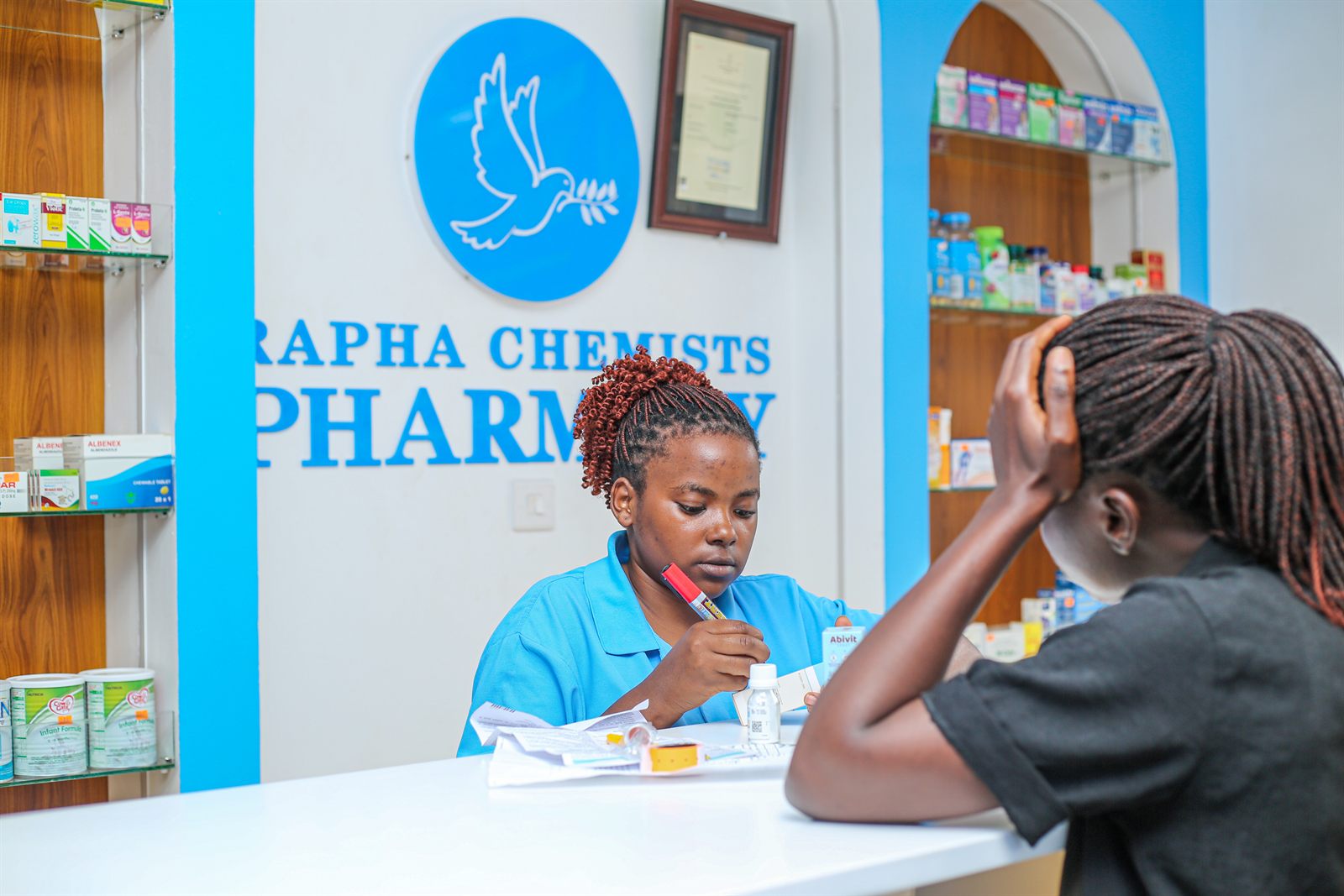 A Rapha Chemists pharmacist helping a customer at the prescription counter